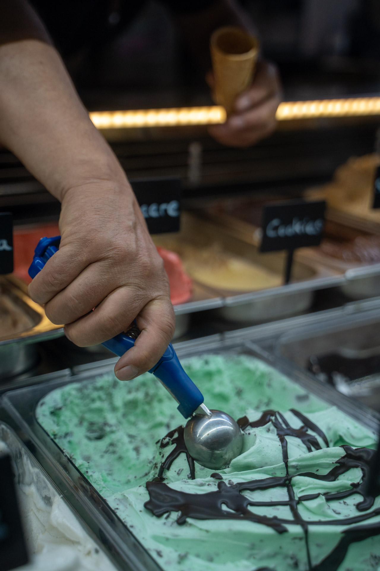 Kugel Eis wird an der Eistheke im Eis-Café Caramello portioniert